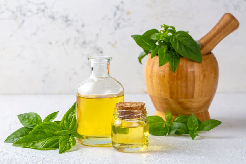 Basil essential oil and fresh leaves on wooden table, closeup Basil essential oil and fresh leaves on wooden table, closeup