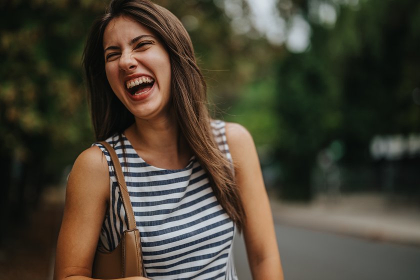 Junge Frau lacht herzlich über sich selbst