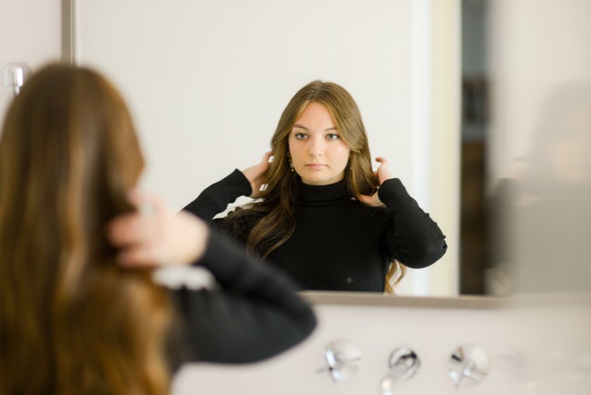 Frau betrachtet sich im Spiegel