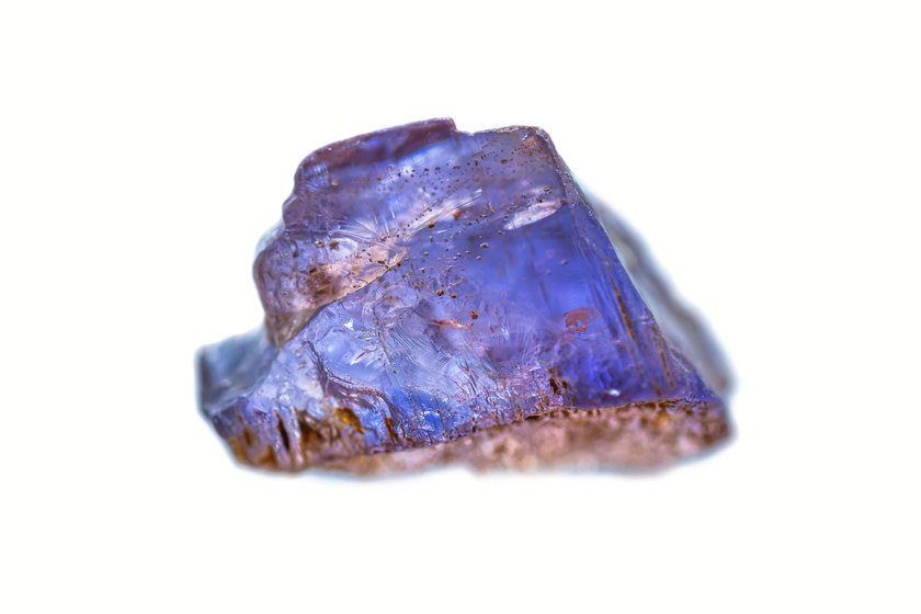 Closeup natural rough Tanzanite gemstone on white background (Zoisite group minerals) (selective focus, shallow DOF)