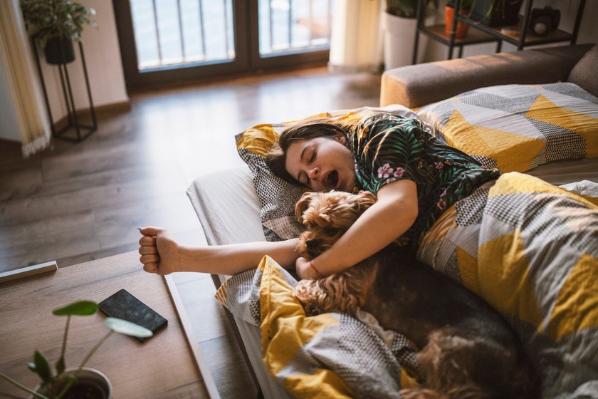 Morgenroutine gegen Stress: Frau kuschelt mit Hund in Bett