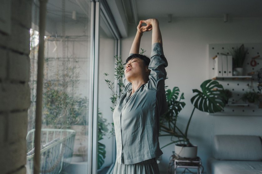 Morgenroutine gegen Stress: Frau stretcht nach dem Aufwachen