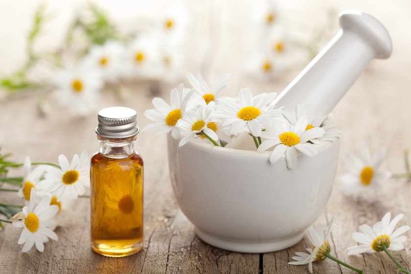 essential oil and camomile flowers in mortar essential oil and camomile flowers in mortar