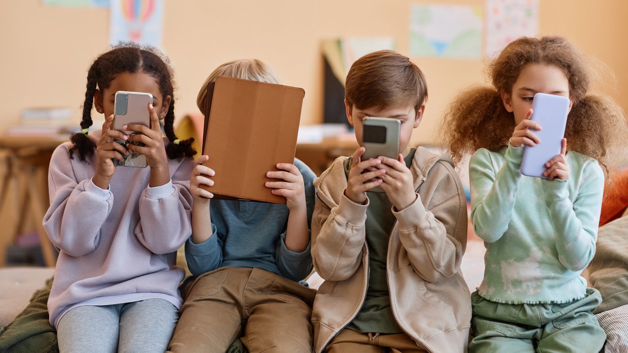 Group of young children holding smartphones and hiding faces, gen Alpha