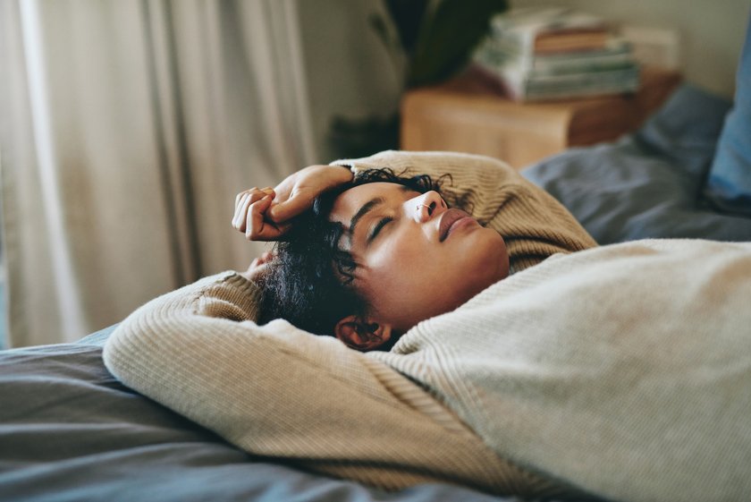 Müde Frau liegt auf dem Bett und döst