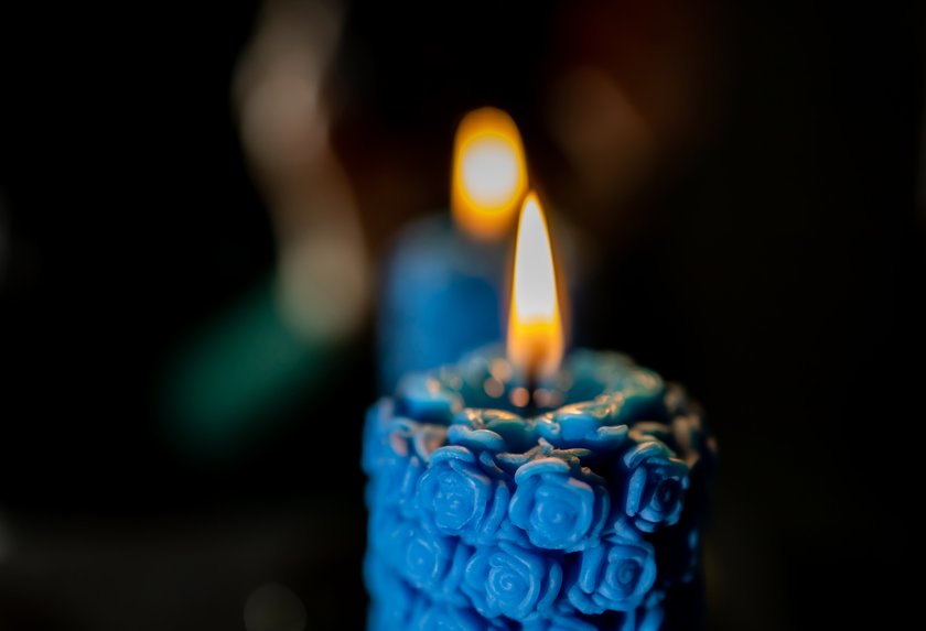 Burning blue candle. Blurred reflection in the mirror