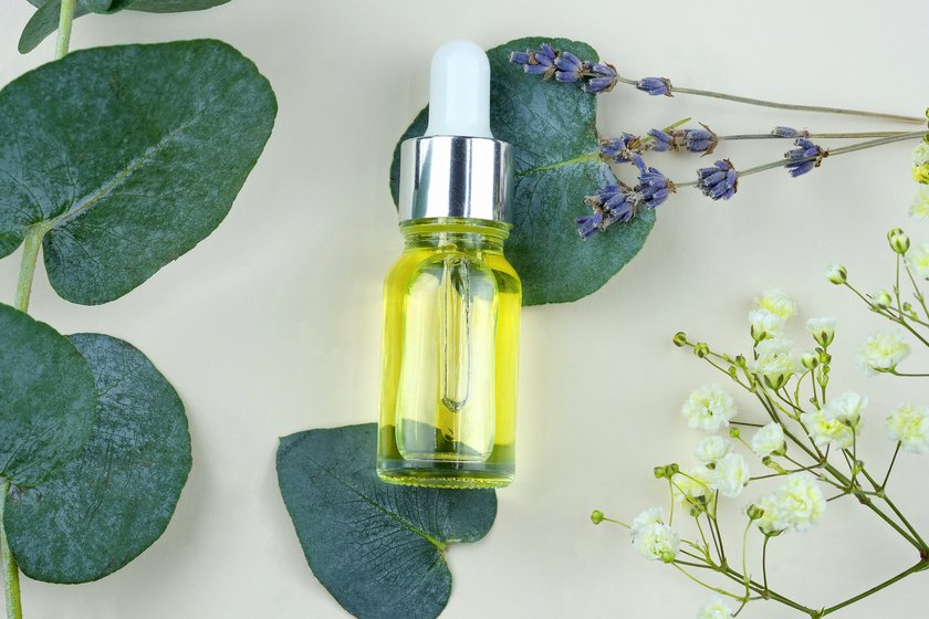 Yellow essential oil in a glass bottle with a dropper top view. Organic eucalyptus oil from eucalyptus bush. Herbal alternative medicine concept. Cuticle oil in a transparent bottle.