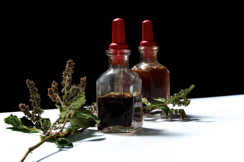 Two small eye dropper bottles with herbal extract essential oils and branch of dried patchouli leaves and flowerss. Oils are patchouli and rosemary. Two small eye dropper bottles with herbal extract essential oils and branch of dried patchouli leaves and flowerss. Oils are patchouli and rosemary.